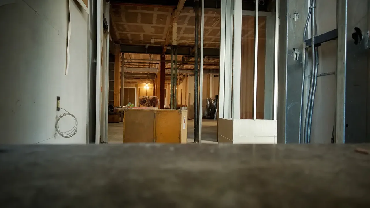 A layered view past foreground objects into a hospitality build-out, illustrating the change-order economy