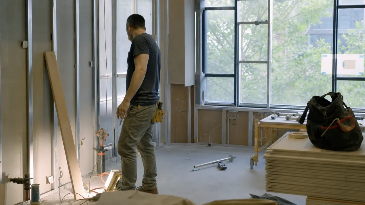 A worker mid-task in a hospitality build-out, illustrating hire a general contractor, or run the trades yourself?