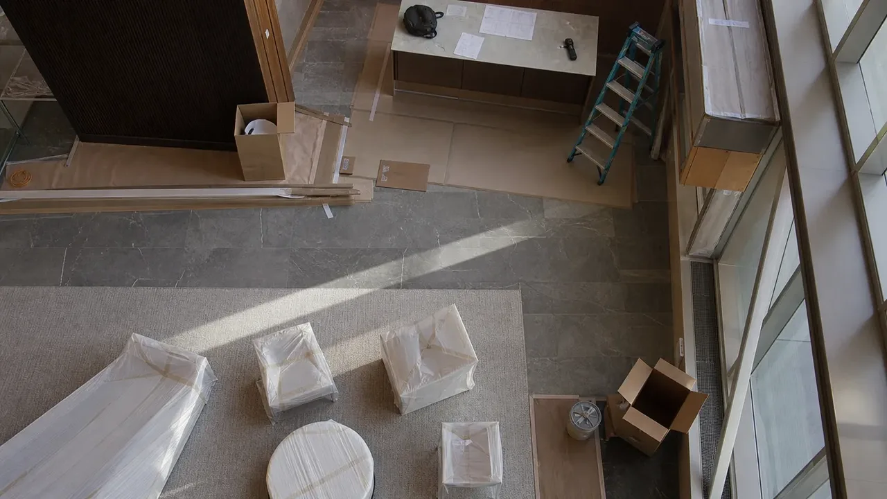 An overhead view of a room under construction with wrapped furniture and a ladder
